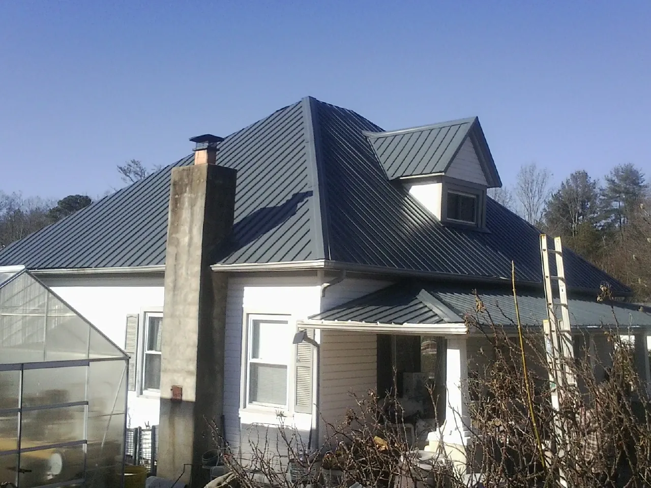 Dark blue standing seam metal roof on a white farmhouse with dormer — Slate & Tile Roof Repair by Roofing Brothers in Mantachie