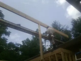 Carpenter setting a ridge beam over a new addition frame — Ice Dam Removal by Roofing Brothers in Mantachie