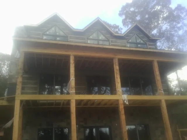 Dormers and porch framing on a large log home under construction — Roof Coating work by our crew in Mantachie