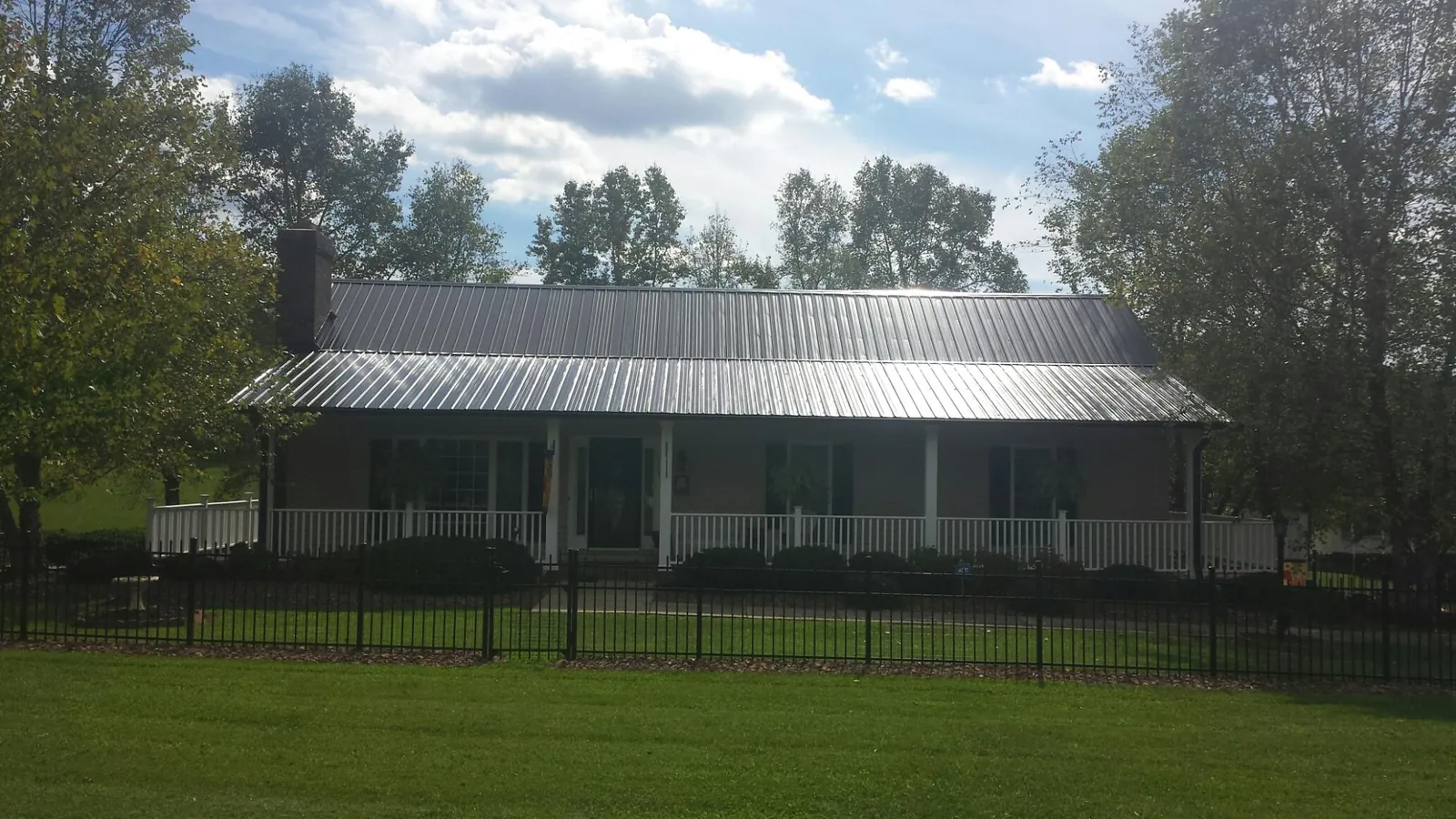 Gray metal roof on a brick ranch with a full width front porch — Gutter Guard Installation work by our crew in Mantachie