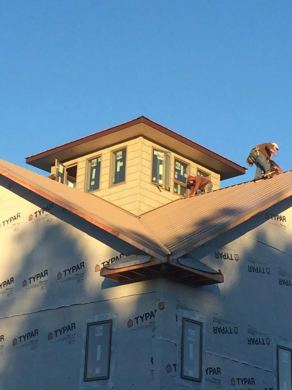 Roofers working around a rooftop cupola on a new metal roof at sunset — Roof Waterproofing in Mantachie by Roofing Brothers